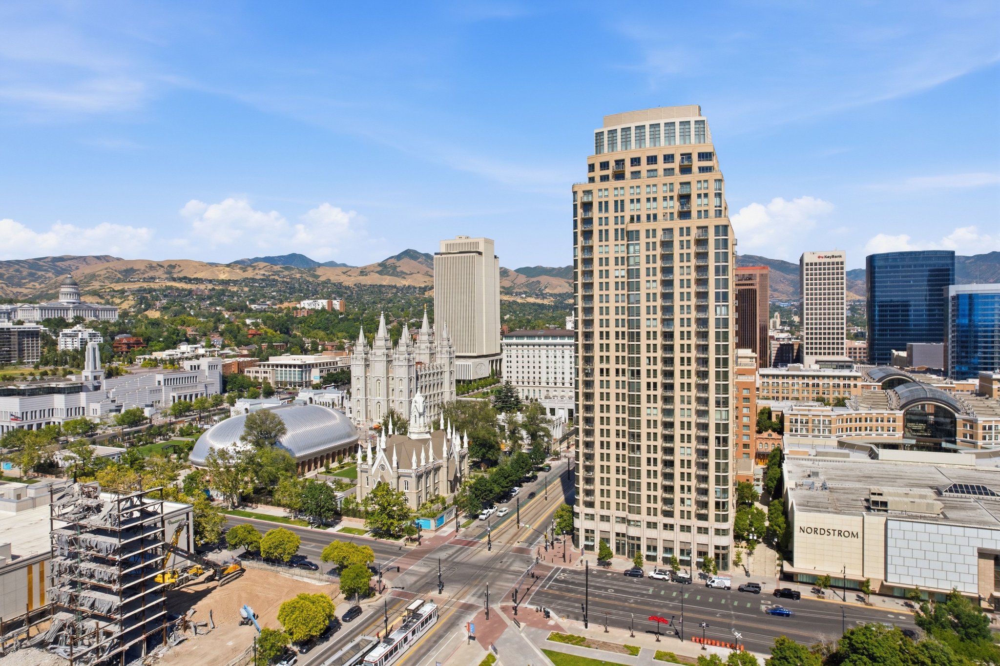 Urban skyline featuring a prominent residential tower with multiple balconies, alongside commercial buildings and historic structures