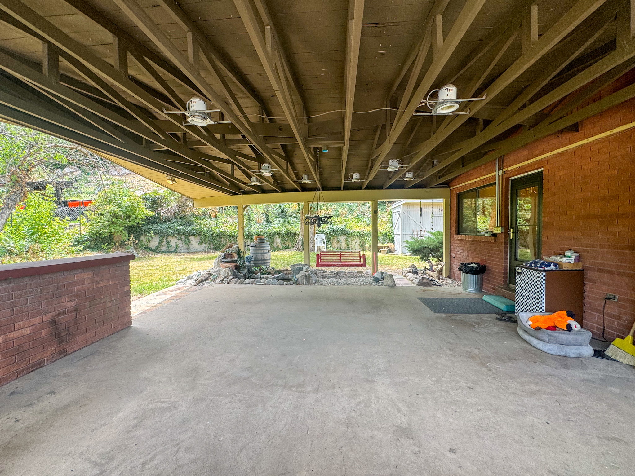 Spacious covered patio with a concrete surface, exposed wood beam ceiling, and recessed lighting