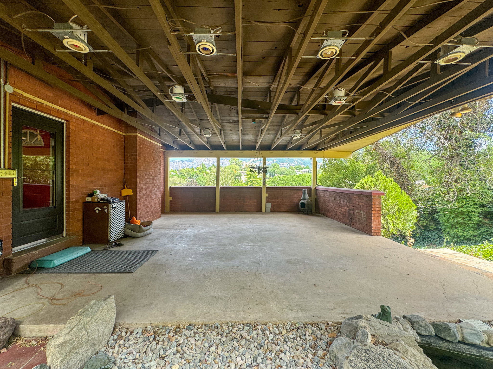 Covered concrete patio with exposed wood beam ceiling and recessed lighting