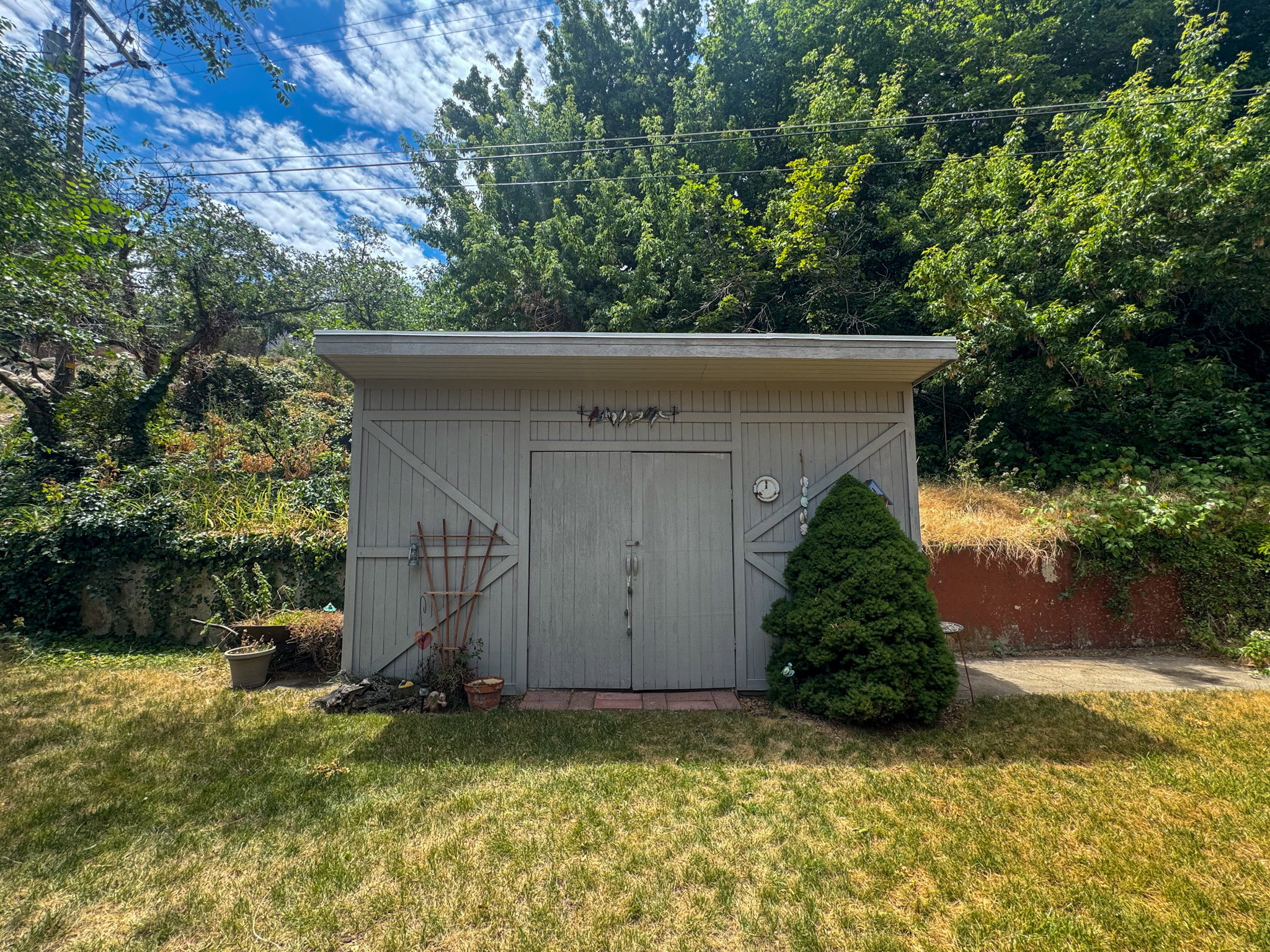 Detached shed featuring double barn doors and an adjacent paved area