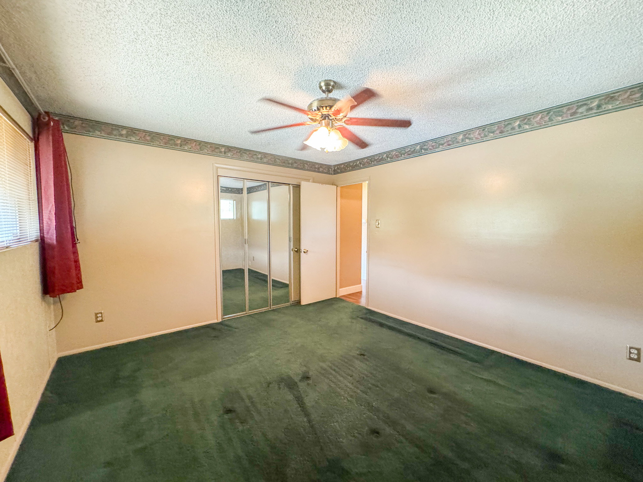 Bedroom featuring wall-to-wall green carpeting, neutral painted walls, and a textured ceiling