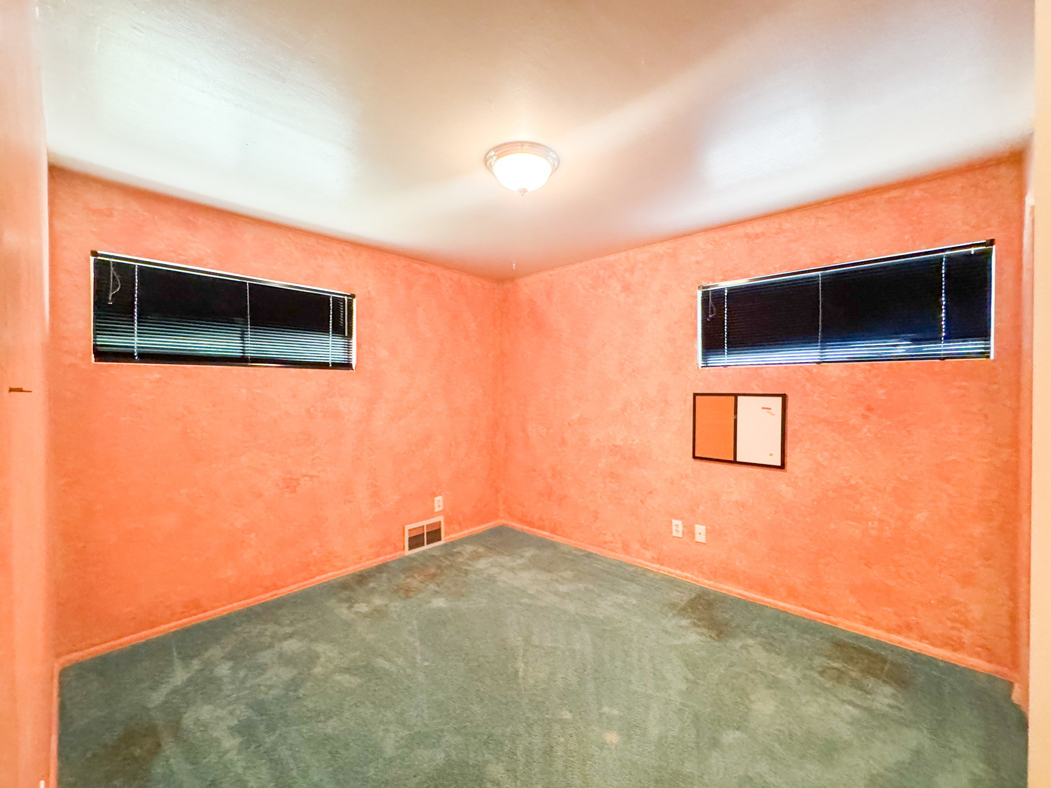 Interior room featuring textured walls, two windows with horizontal blinds, and ceiling-mounted lighting