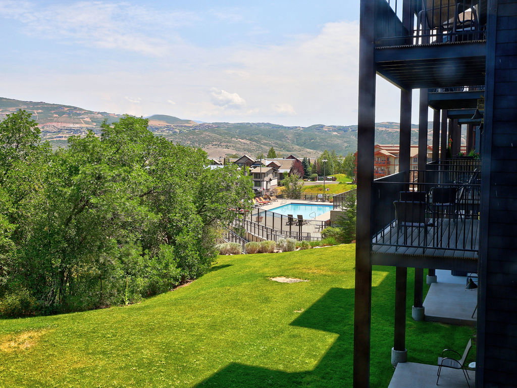 Expansive green lawn with mature trees and mountain scenery