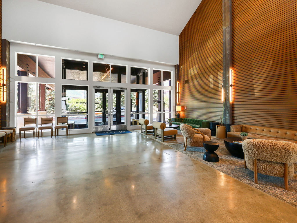 Spacious lobby featuring polished concrete flooring, a dramatic wood-paneled accent wall, and floor-to-ceiling windows