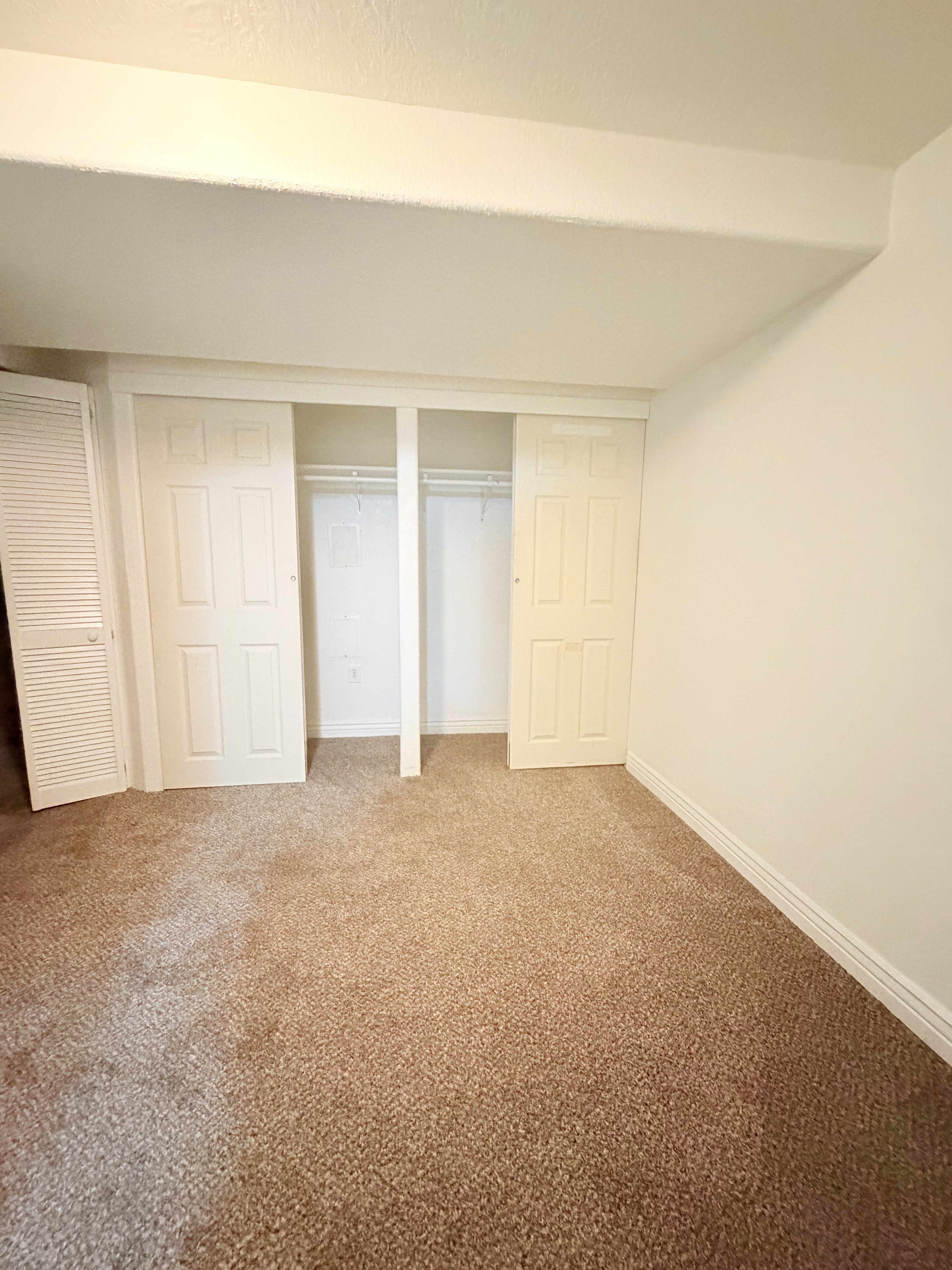 Wall-to-wall carpeting with a light brown hue, complemented by white baseboards and walls