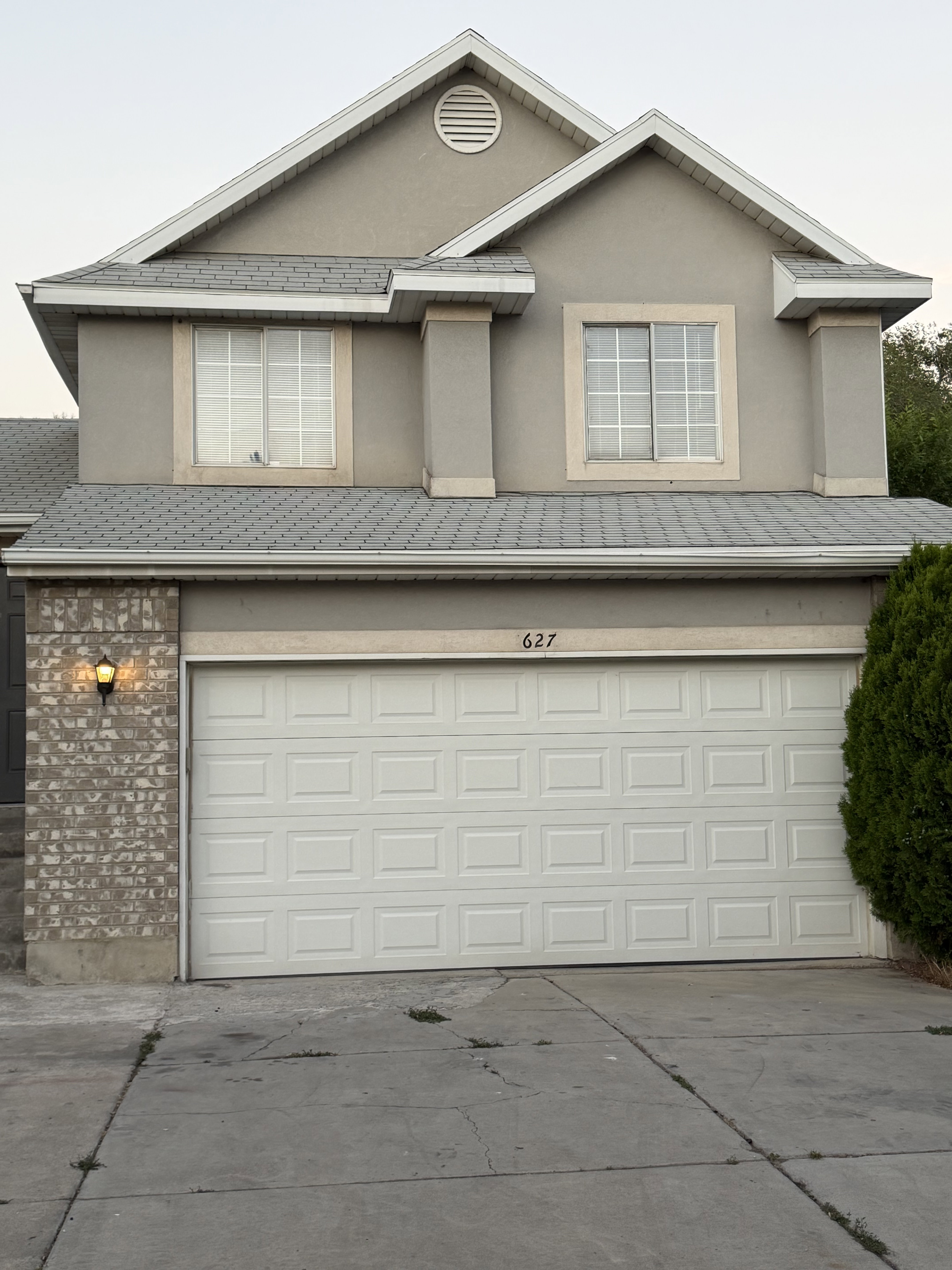 Exterior with gray stucco finish, white trim, and a prominent two-car garage
