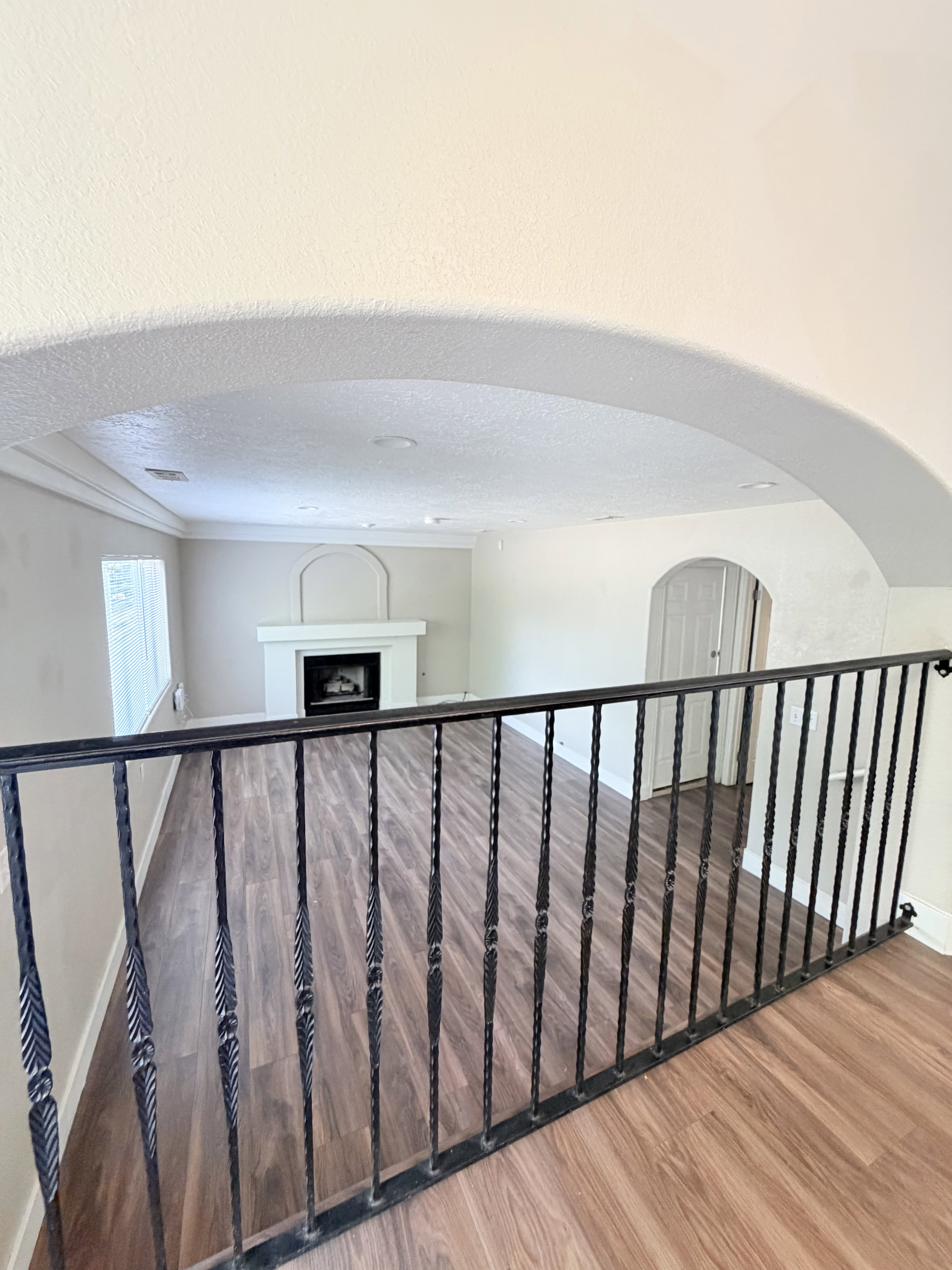 Archway entry from upper level featuring wrought iron railing