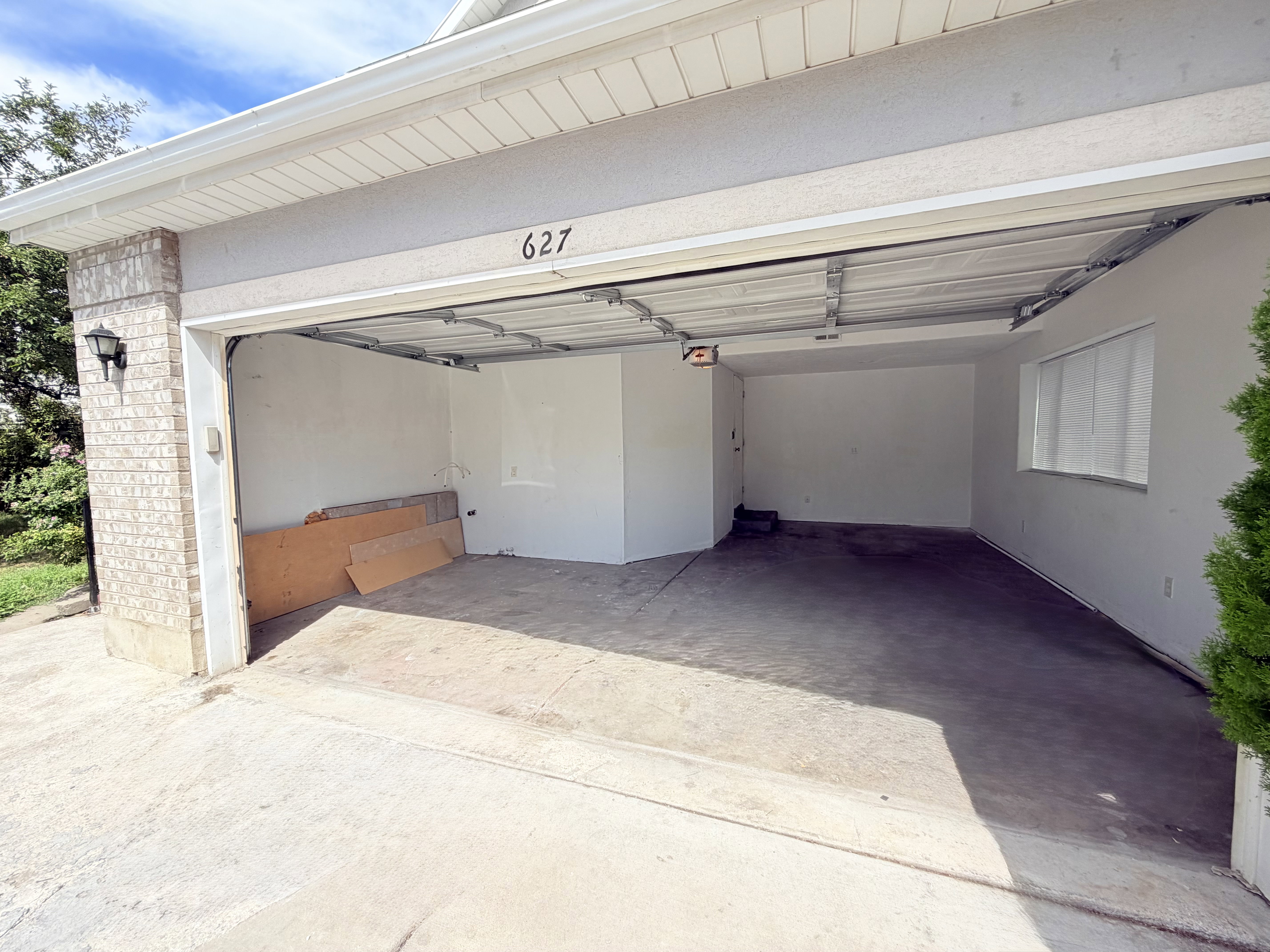 Two-car garage with concrete flooring, stucco exterior, and brick accents