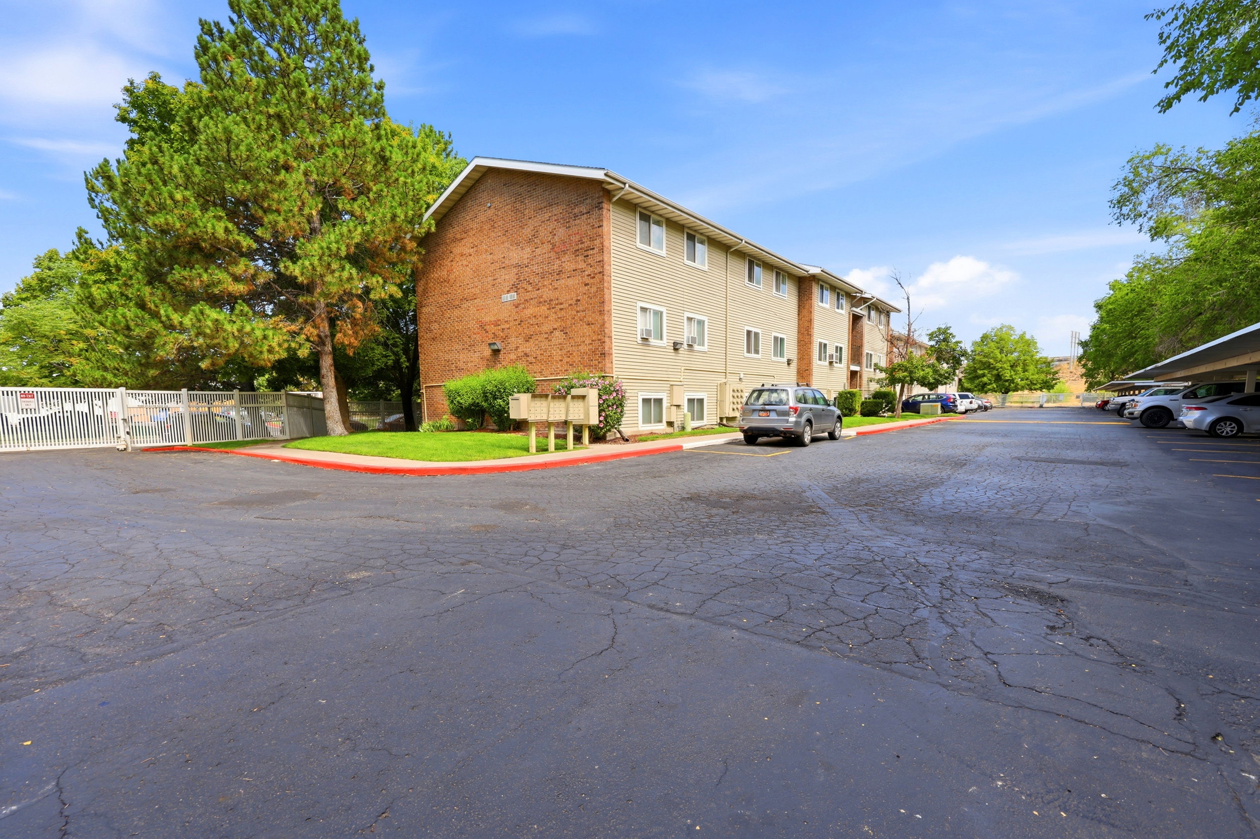 Building exterior featuring brick and siding finishes, multiple windows, and individual air conditioning units