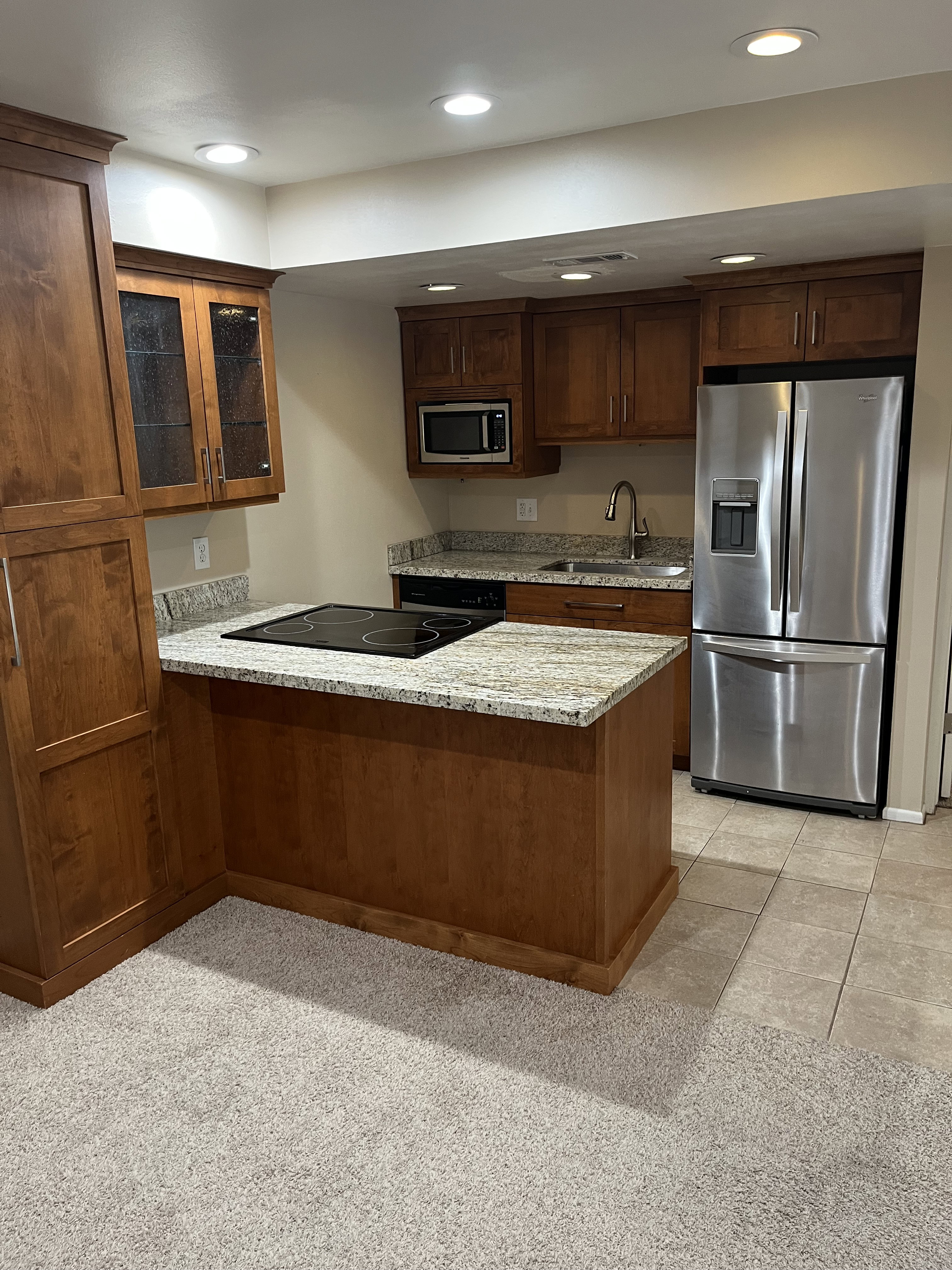 Kitchen featuring wood cabinetry, granite countertops, stainless steel appliances, and an electric cooktop