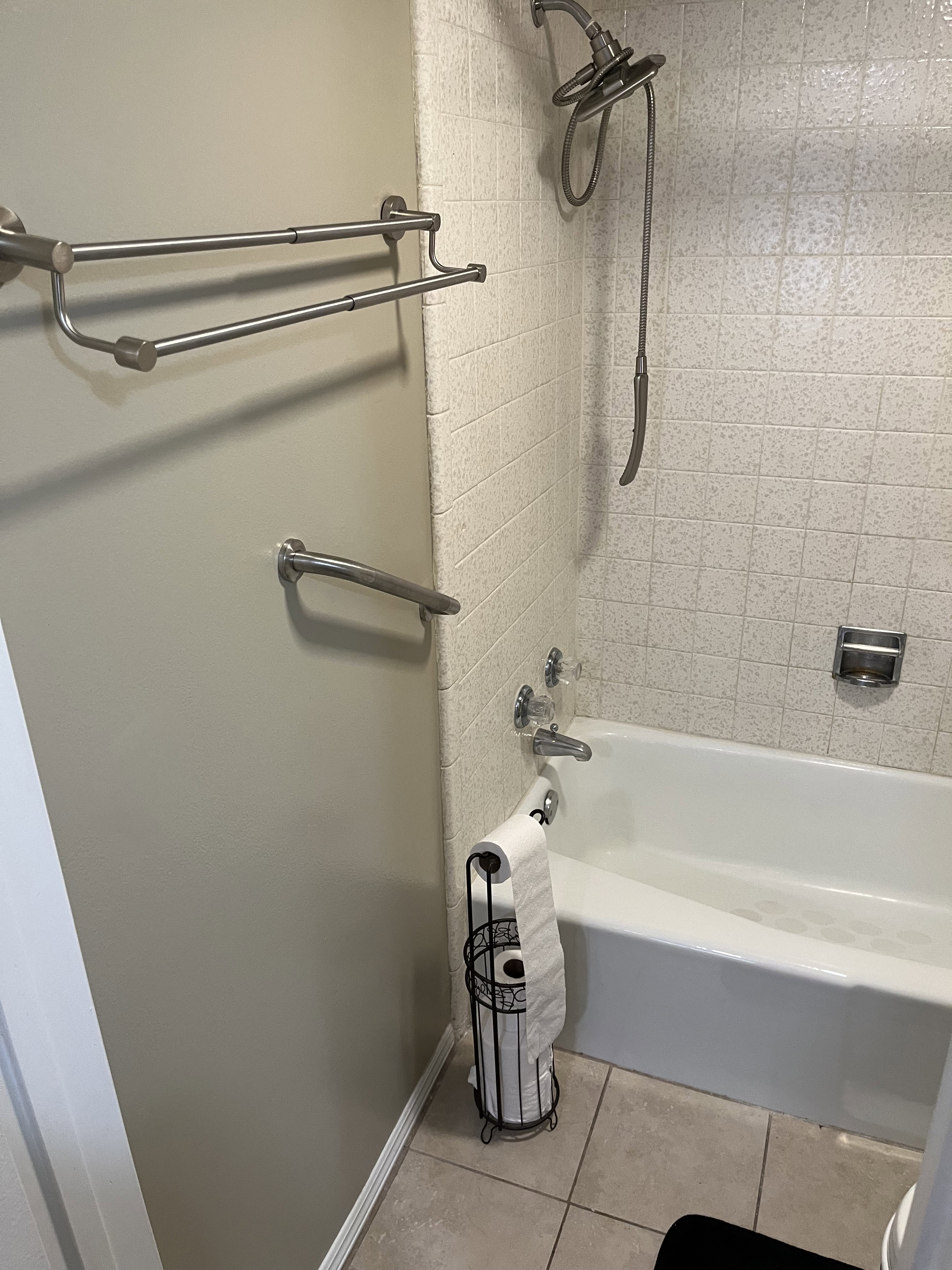 White tiled shower surround with a fixed showerhead and handheld sprayer