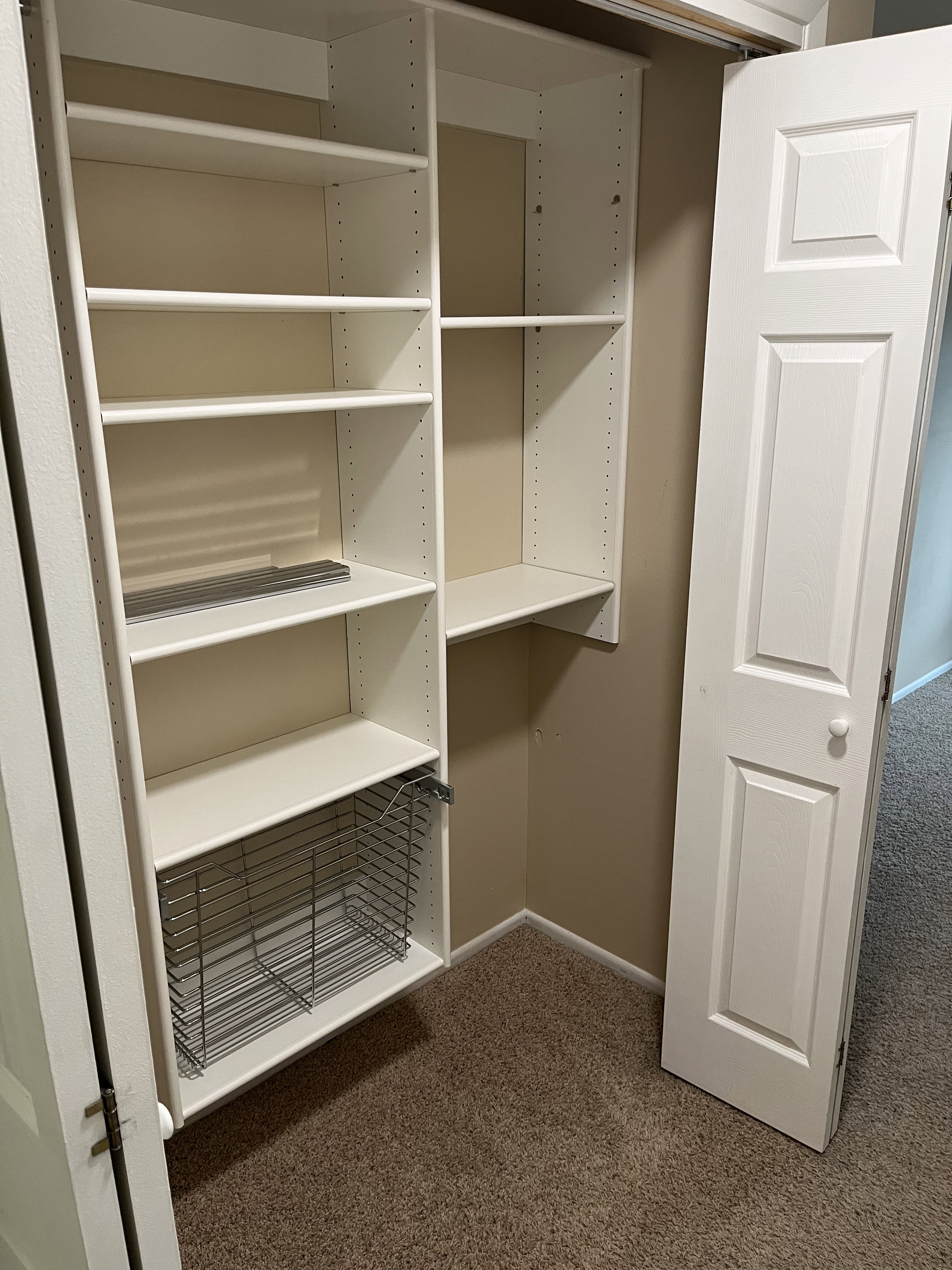 Integrated closet system featuring multiple white shelving units and a pull-out wire basket
