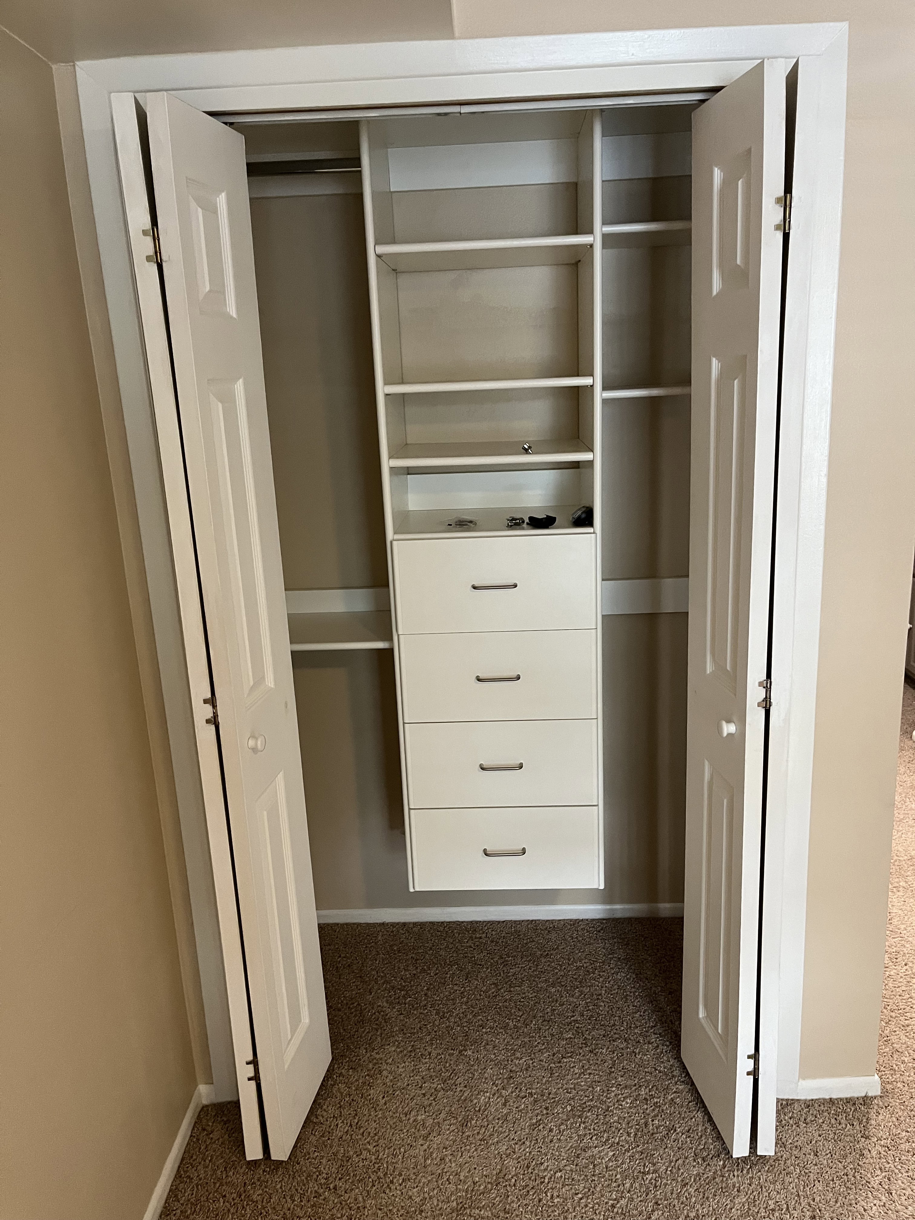 Integrated closet system featuring multiple shelves and four drawers with contemporary hardware