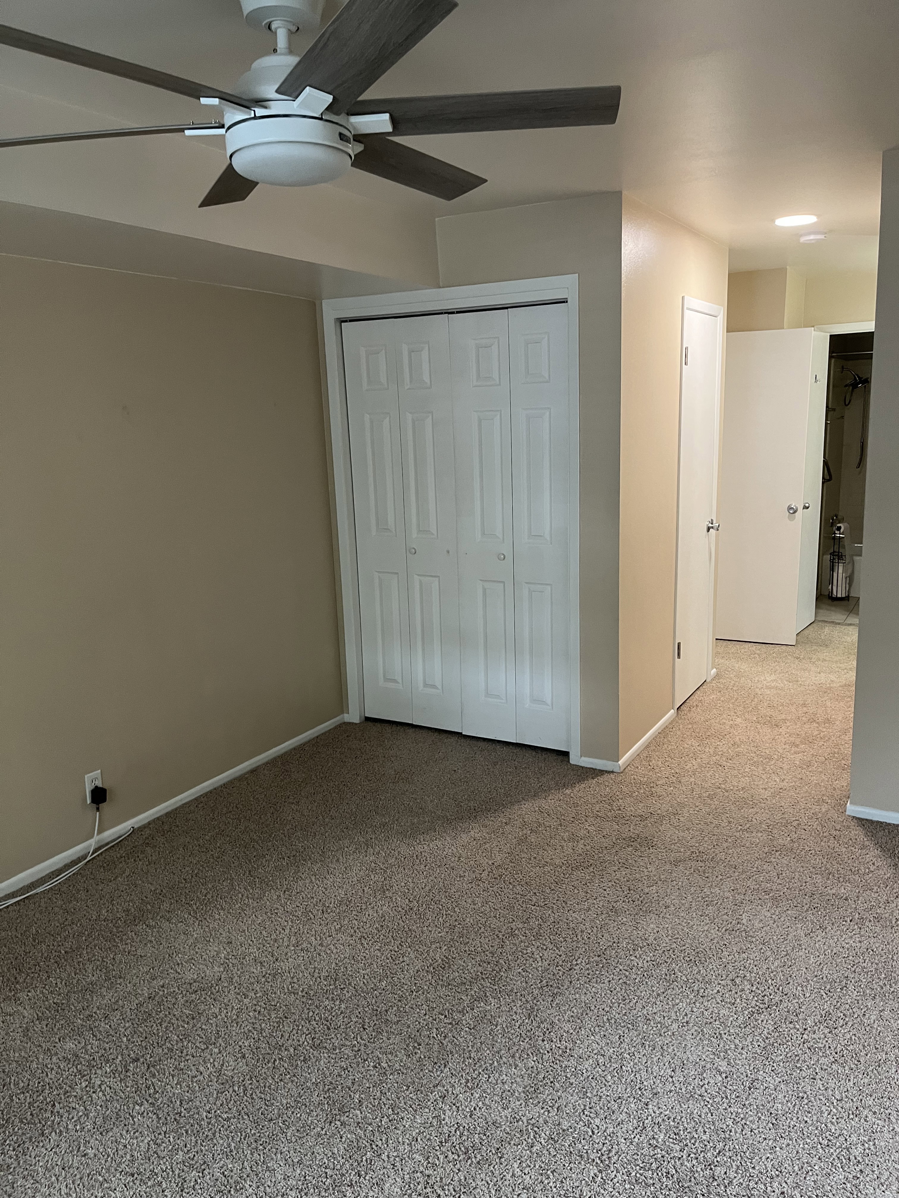 Carpeted interior space featuring a ceiling fan with integrated lighting, bi-fold closet doors, and recessed ceiling lights in the hallway