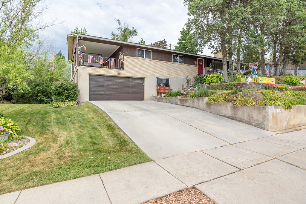 Split-level residence featuring a two-car garage, concrete driveway, and a front balcony
