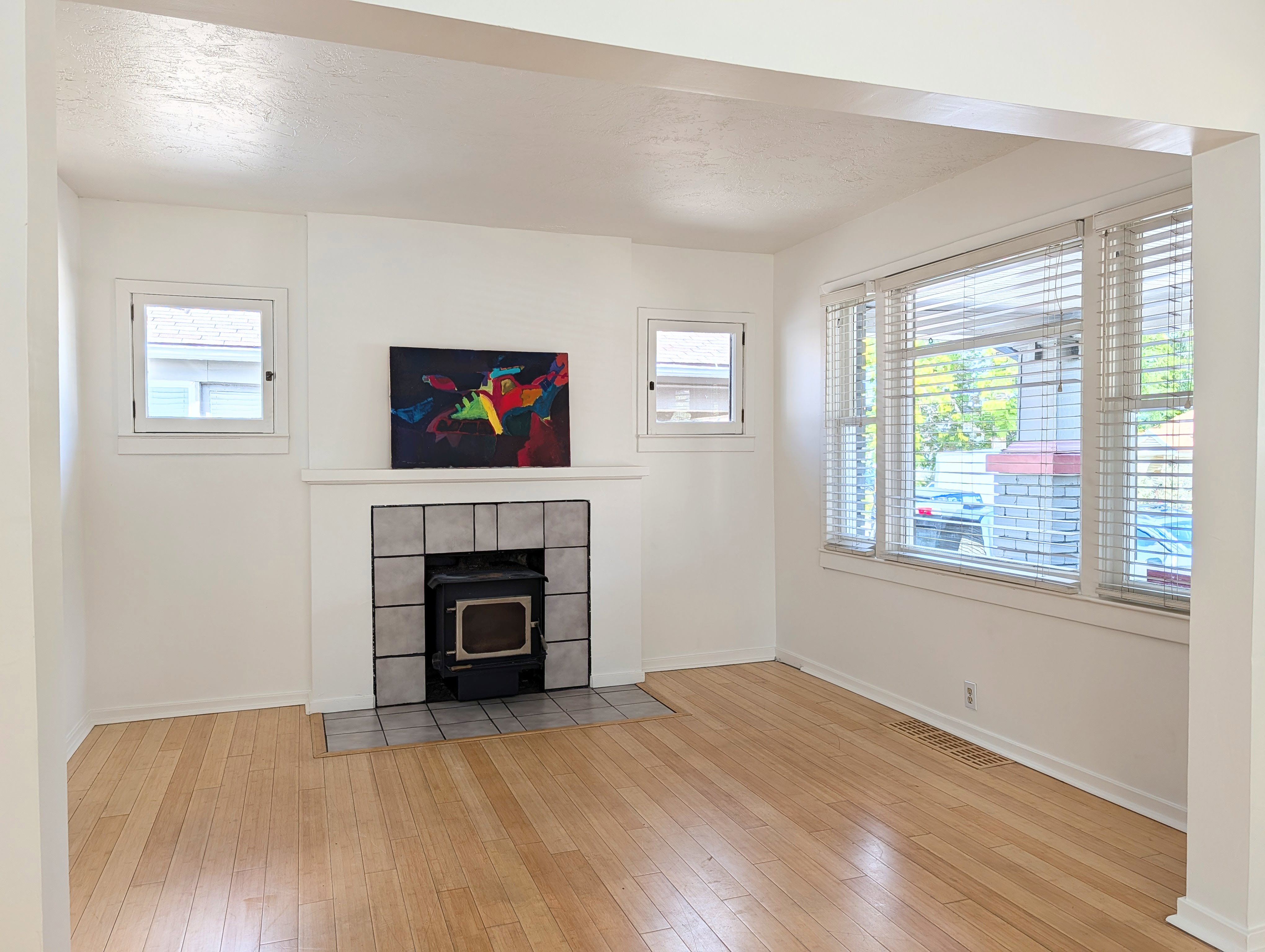 Spacious interior featuring light wood-finish flooring, a fireplace with a tiled surround, and multiple windows