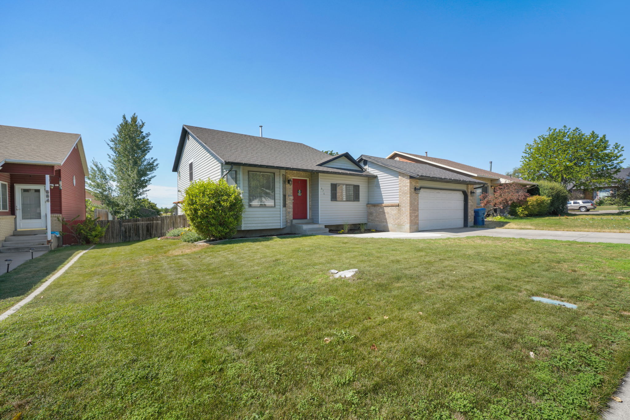 Ranch-style residence featuring light-colored siding and a red entry door