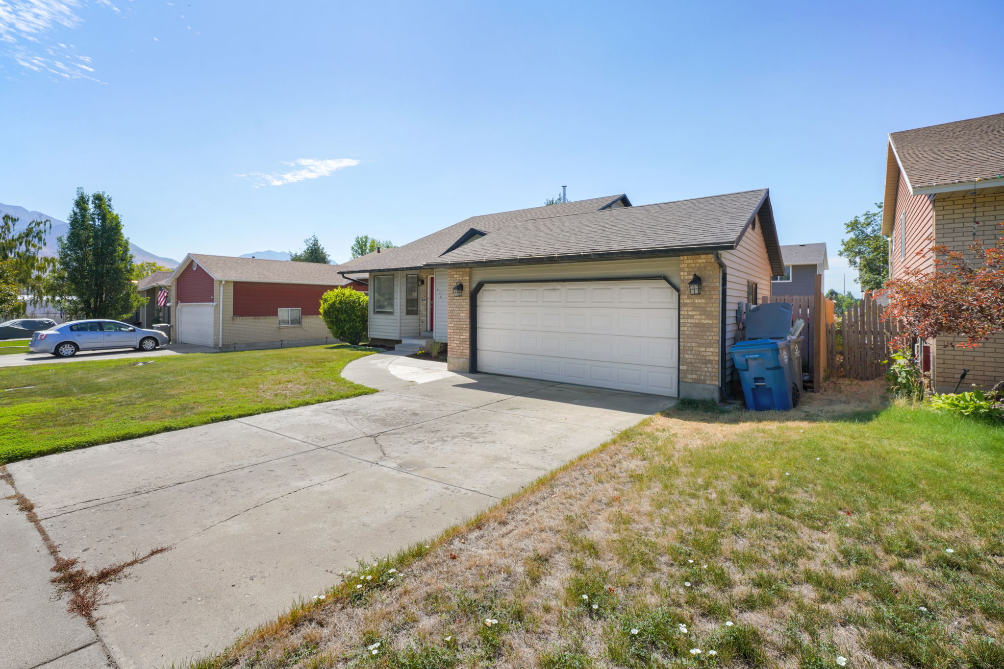 Front exterior featuring a two-car garage, concrete driveway, and mature landscaping