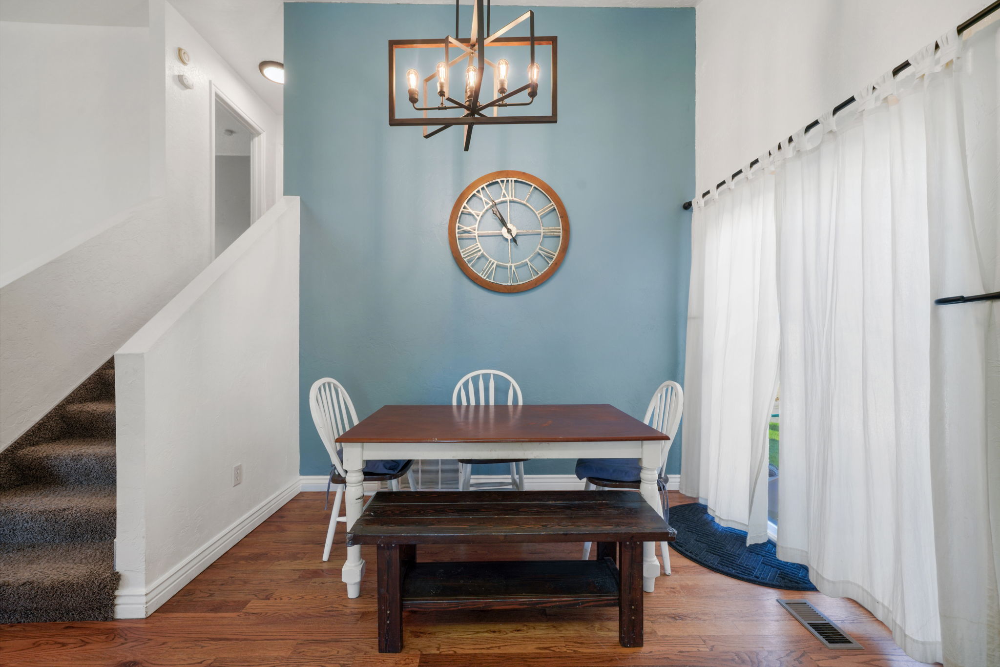 Dining area featuring wood-finish flooring, a contemporary chandelier, and a blue accent wall