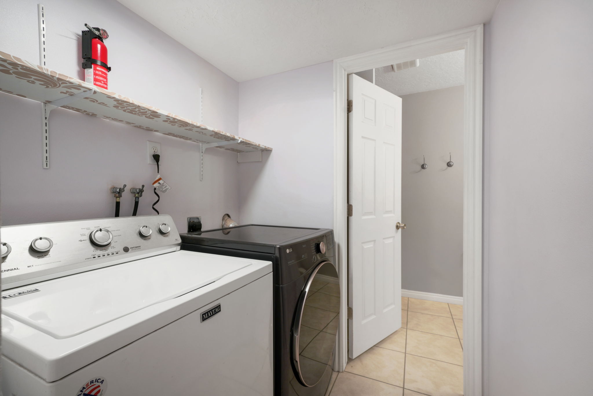 Dedicated laundry area featuring tile flooring, light gray walls, and built-in shelving
