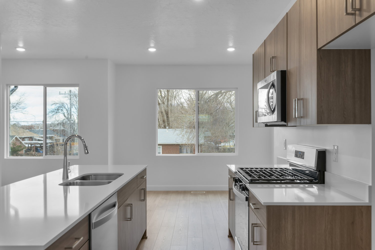 Contemporary kitchen featuring wood-finish cabinetry, stainless steel appliances, and white countertops
