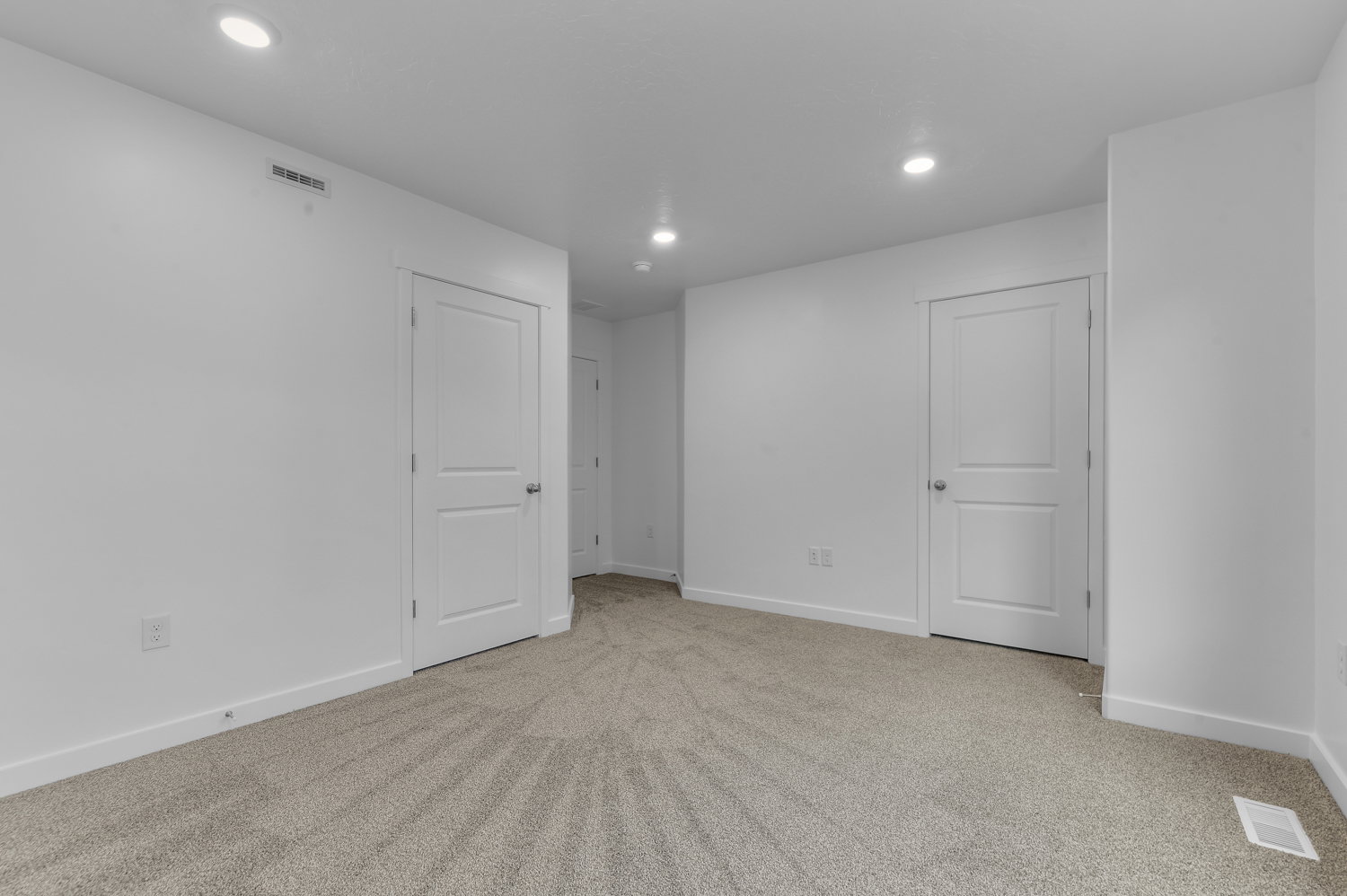 Carpeted room featuring white walls, recessed lighting, and multiple white two-panel interior doors