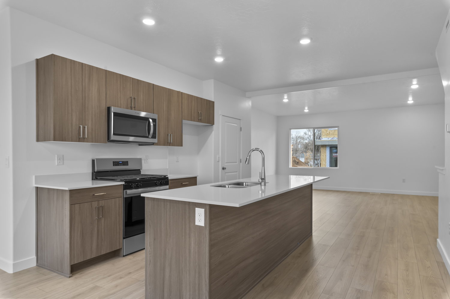 Modern kitchen featuring wood-grain cabinetry, stainless steel appliances, and light-tone countertops