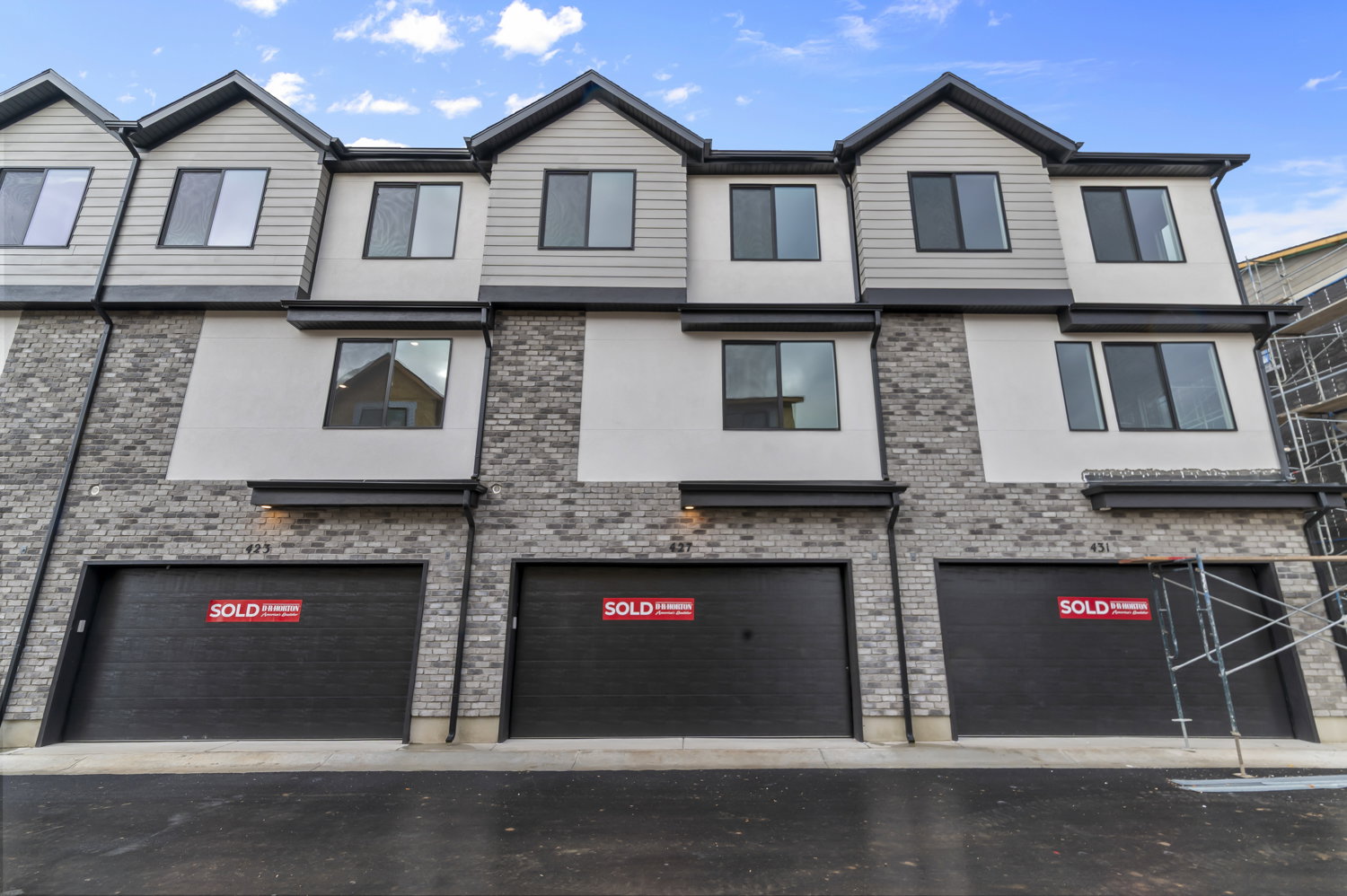 Contemporary multi-story townhome exterior featuring a striking combination of light brick and horizontal siding