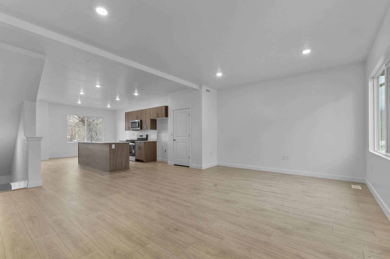 Open-concept living space featuring wood-finish flooring, recessed lighting, and a white color palette