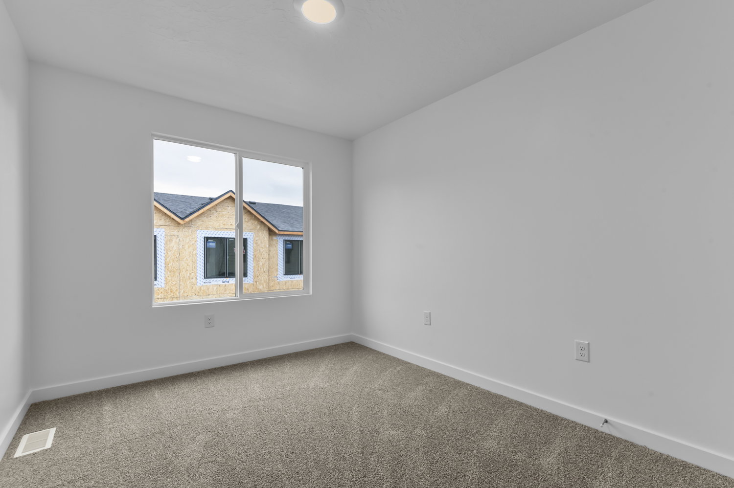 Neutral-toned carpeted room featuring white walls and baseboards