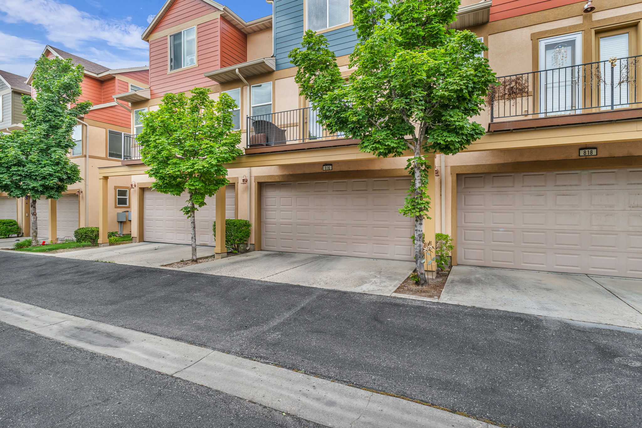 Multi-level townhome exterior featuring an attached two-car garage, stucco siding, and a private balcony with wrought iron railing