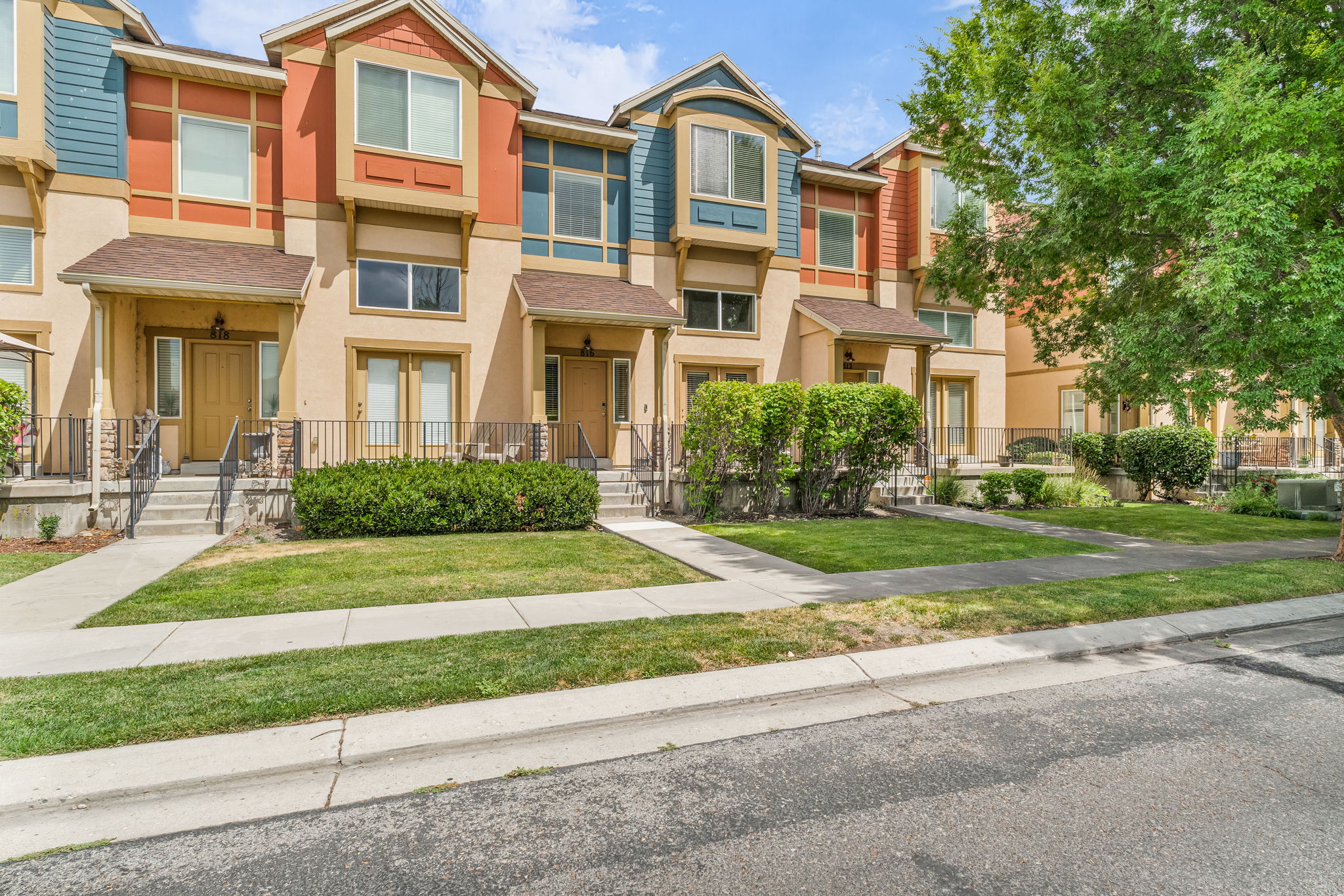 Multi-story townhome exterior featuring varied siding colors, covered entryways, and individual patios