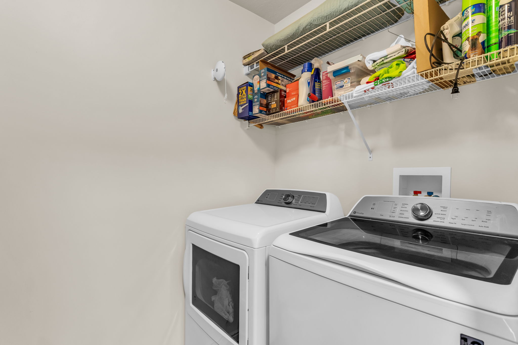 Laundry area featuring neutral wall tones, wire shelving, and utility hookups