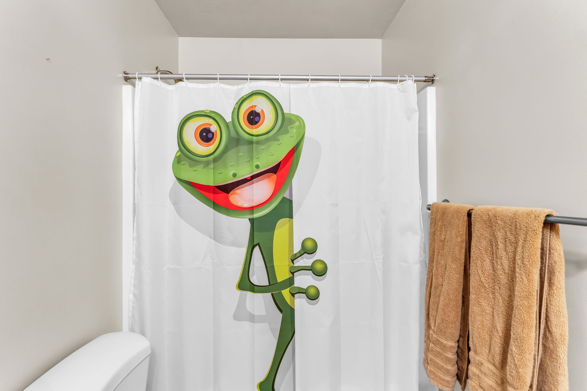 Bathroom featuring a full-sized shower enclosure with a shower rod, a toilet, and a wall-mounted towel bar