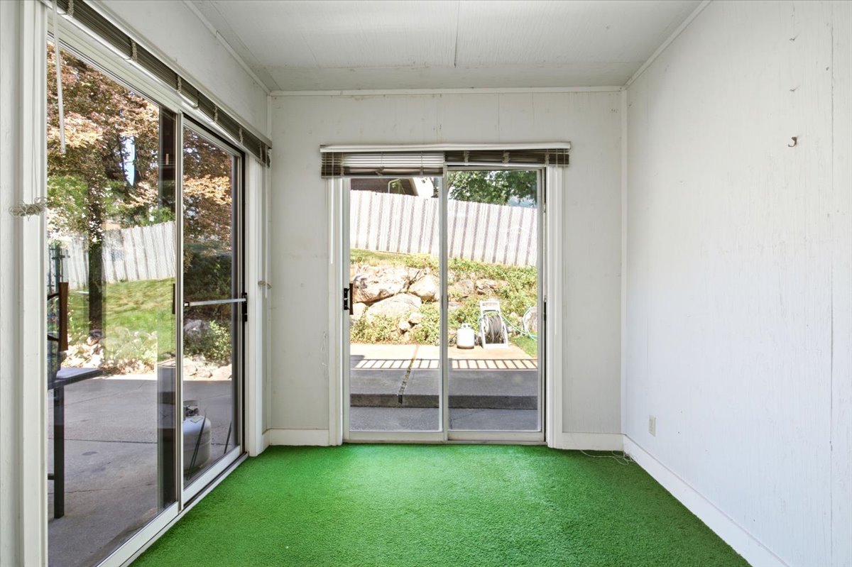 Sunroom featuring two sets of sliding glass doors, white paneling, and green carpeting