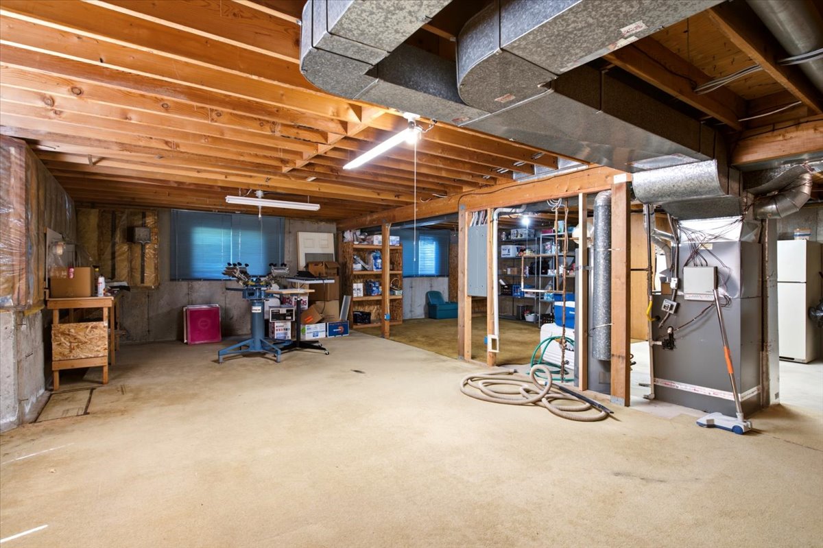 Expansive unfinished basement featuring exposed wood joists and concrete walls