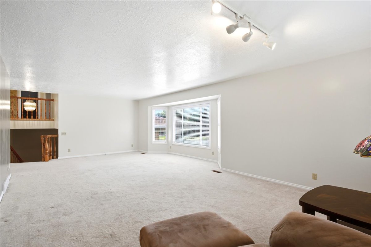 Spacious room featuring light-toned carpeting, neutral wall finishes, and a bay window providing natural illumination