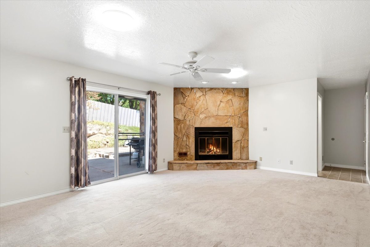 Stone-clad fireplace with hearth, complemented by a ceiling fan with integrated lighting