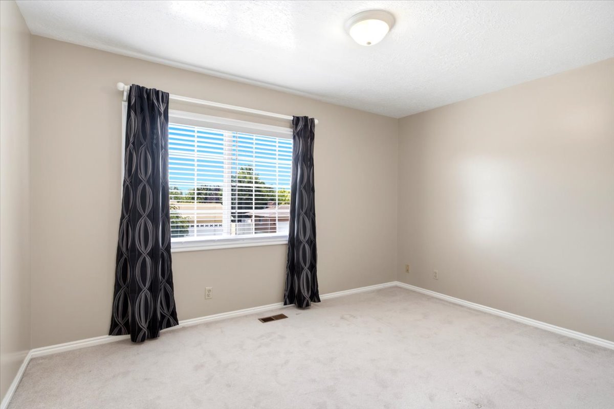 Neutral-toned room featuring a window with horizontal blinds and dark patterned drapes