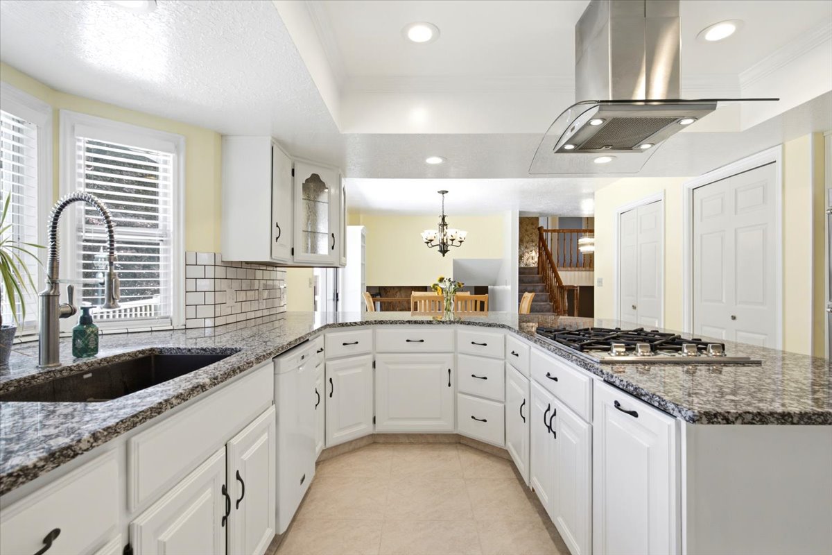Kitchen featuring white cabinetry, speckled countertops, a built-in gas range with a stainless steel range hood, an undermount sink, and recessed lighting