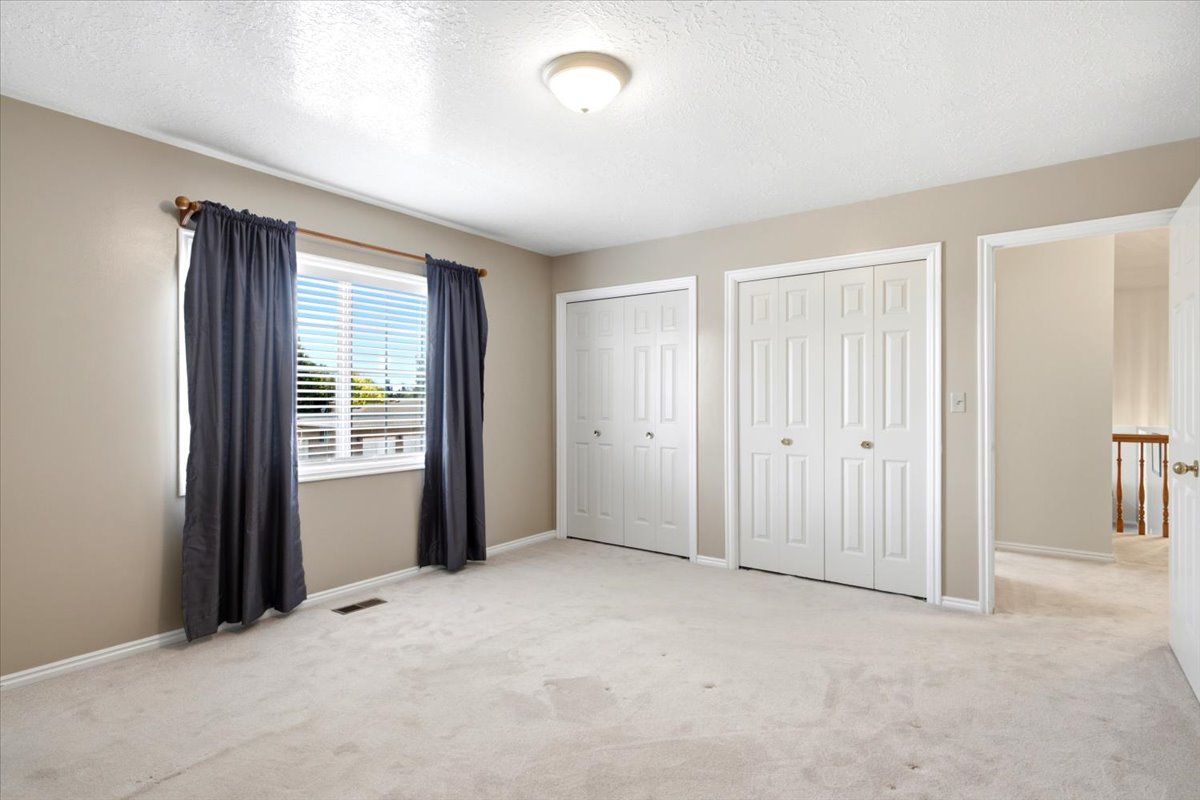Carpeted room with a double-pane window, two panel bi-fold closet doors, and recessed ceiling light fixture