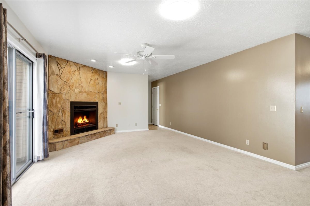 Spacious living area featuring a stone-clad fireplace with hearth, recessed lighting, and a ceiling fan
