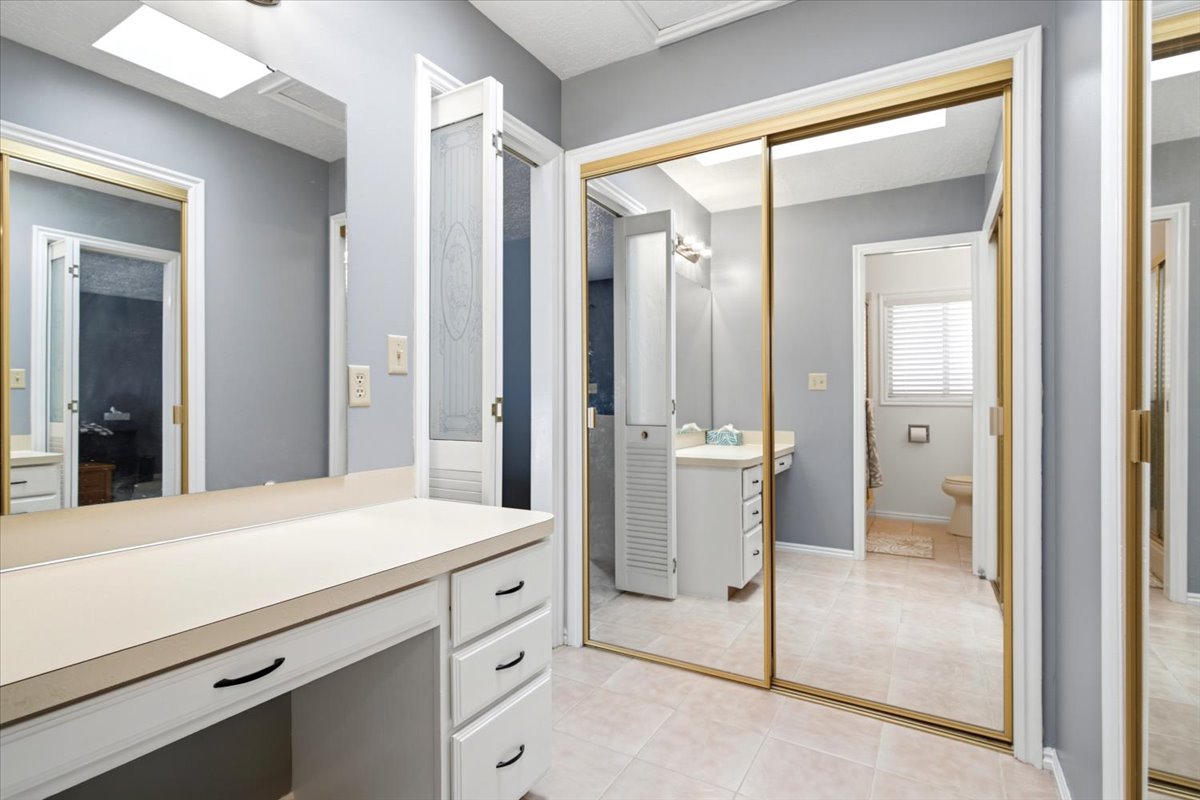 Sliding mirrored wardrobe doors complement a vanity with built-in storage and an integrated countertop
