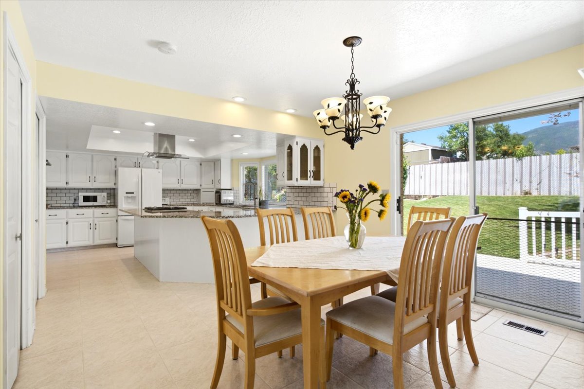 Open-concept kitchen and dining area featuring light-toned flooring, white cabinetry, a kitchen island, and a sliding glass door opening to the exterior