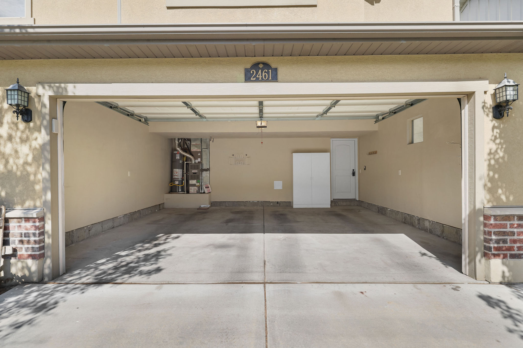 Attached two-car garage featuring a concrete floor, painted interior walls, overhead lighting, and two exterior sconces