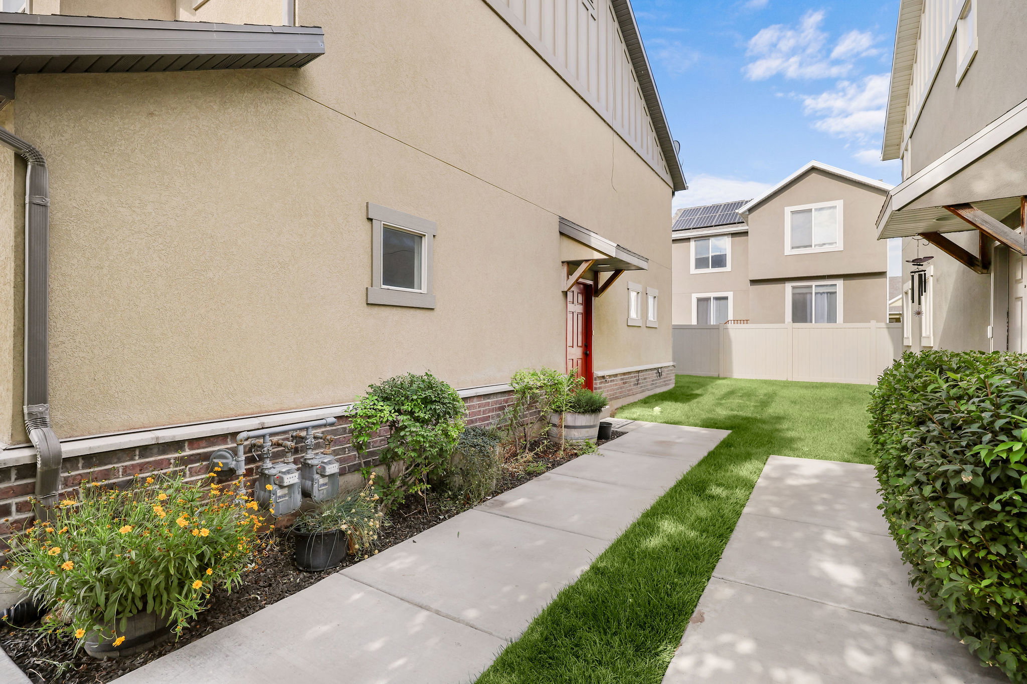 Private outdoor space featuring a manicured lawn, concrete pathway, and established perimeter shrubs