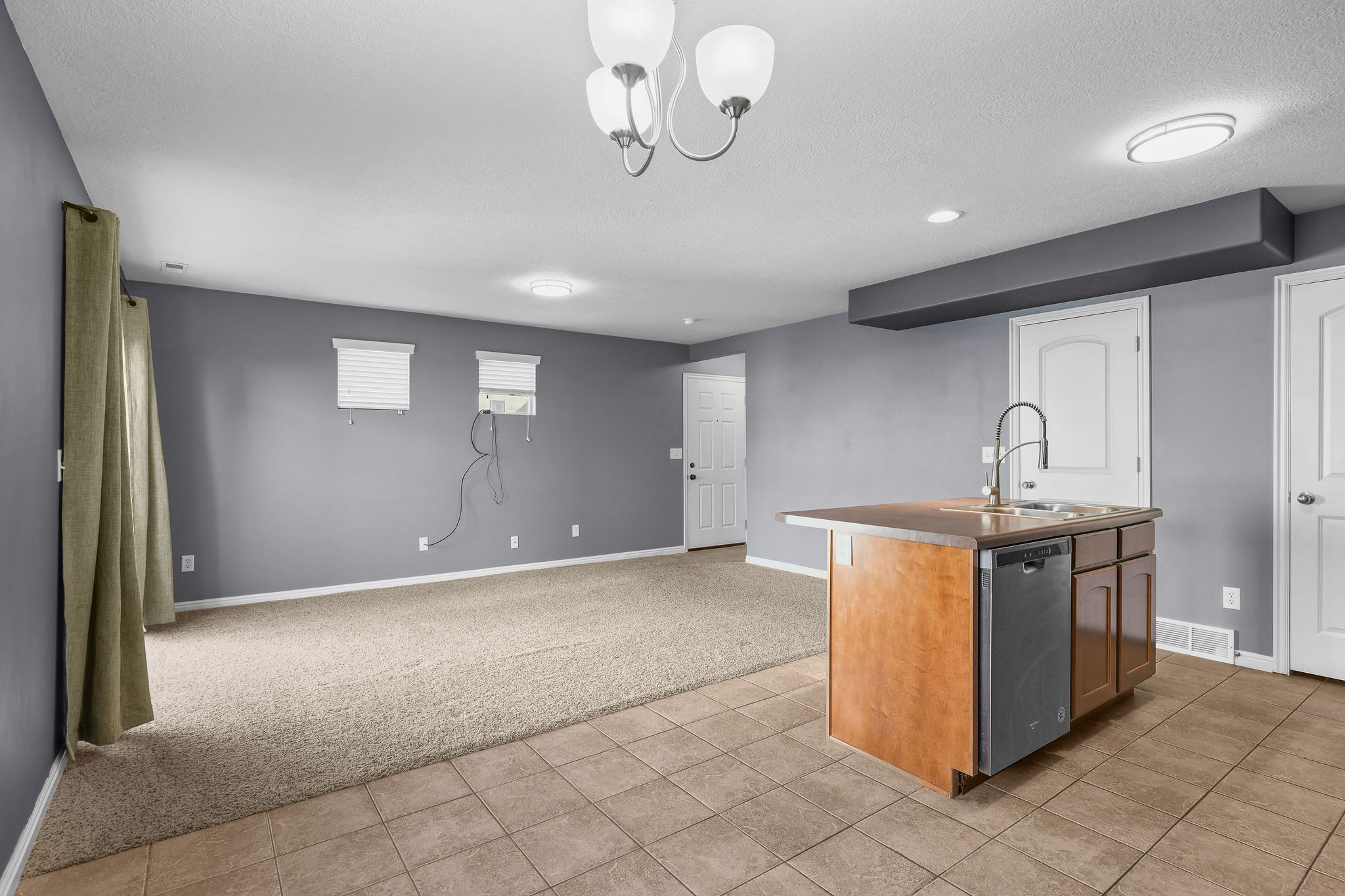 Functional kitchen island featuring wood-finish cabinetry, a stainless steel dishwasher, and a gooseneck faucet