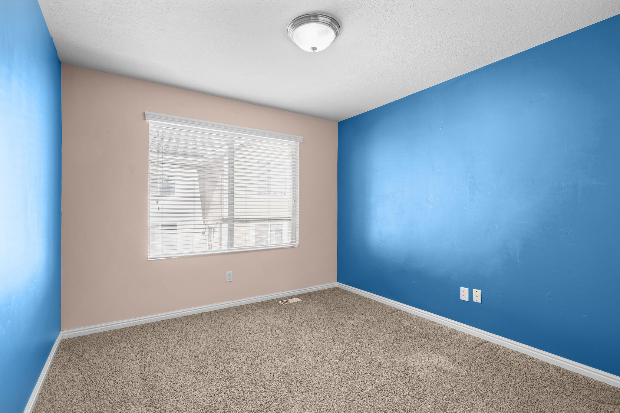 Bedroom featuring light-toned carpeting and contrasting blue and beige wall finishes