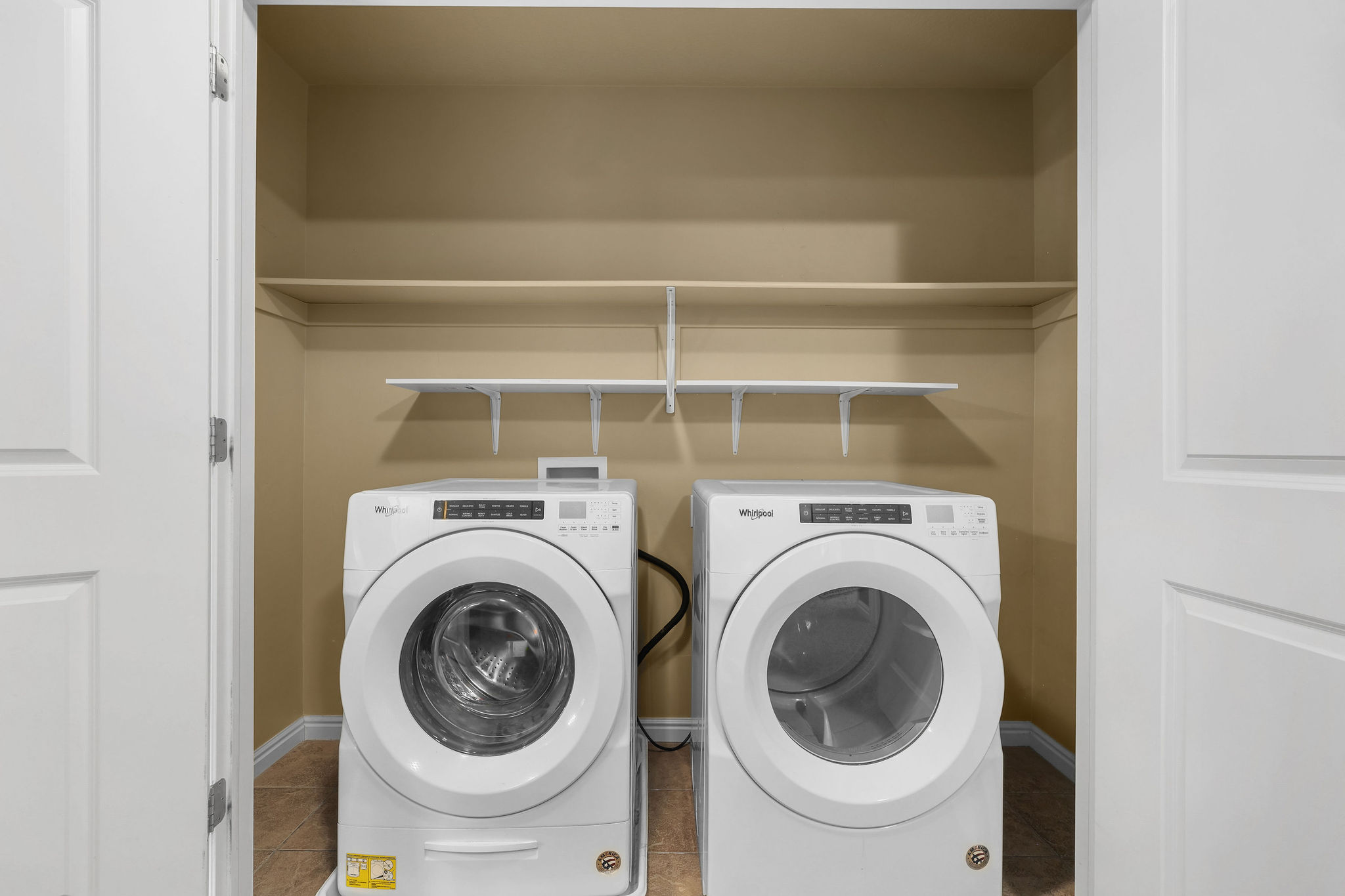 Laundry closet featuring a front-load washer and dryer, built-in shelving, and neutral wall tones