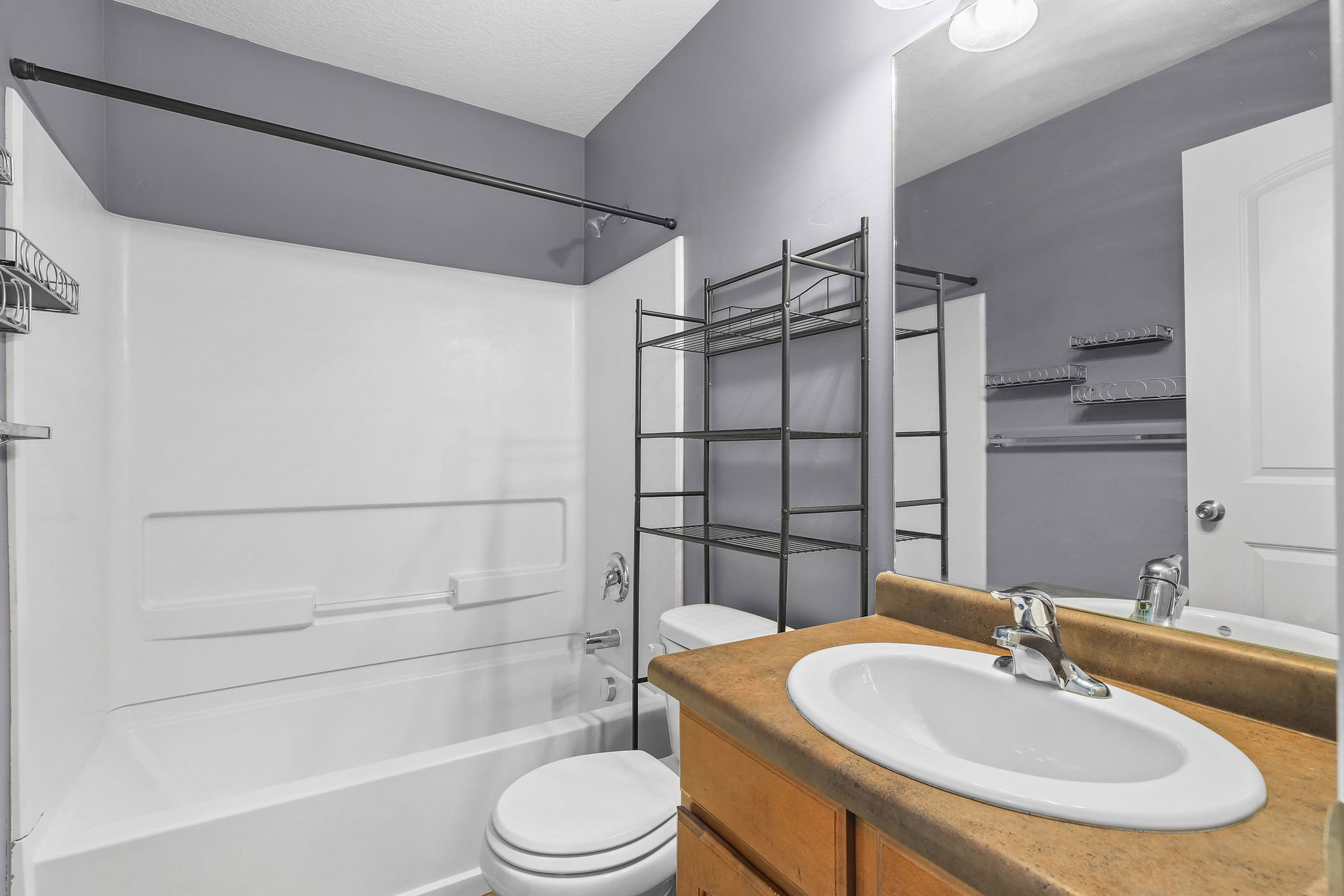 Bathroom featuring a white tub-shower combination, a vanity with an integrated sink, and an expansive mirror